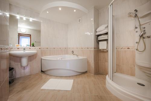 a white bathroom with a tub and a sink at Hotel Panon in Hodonín