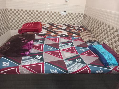 a bed with a colorful comforter and pillows on it at Shri Shyama seva kunj in Vrindāvan