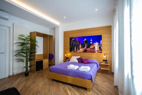 a bedroom with a bed with purple sheets and a painting at Maqueda Mood in Palermo
