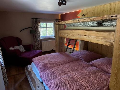 a bedroom with two bunk beds and a chair at Ferienhaus Hutznhaisl in Bärenstein