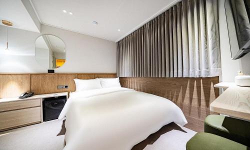 a bedroom with a large white bed and a mirror at 신촌 APL Hotel in Seoul