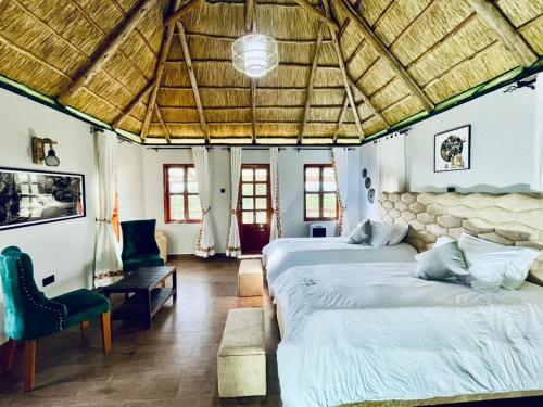 a bedroom with two beds and a chair in a room at Ewafe Safari Lodge-Murchison in Wanseko