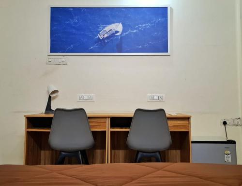 a bedroom with two chairs and a tv on the wall at Bern Hostel By Vibe Village in Pune