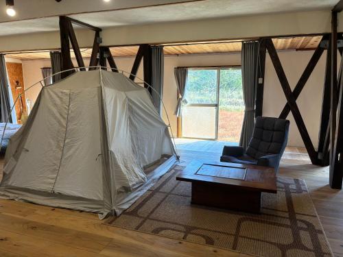 a room with a tent and a chair and a table at 掘っ立て小屋遊々 in Mine
