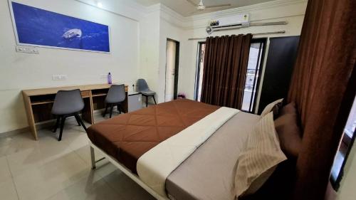 a bedroom with a bed and a desk and chairs at Bern Hostel By Vibe Village in Pune