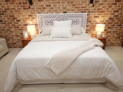 a bedroom with a white bed with a brick wall at The Honeypot in Balmoral