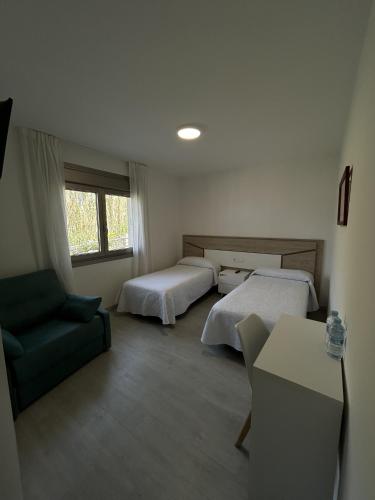 a hotel room with two beds and a couch at Habitaciones A Postiña in Areas