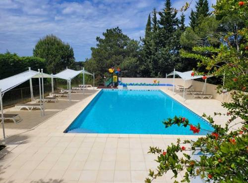 a large swimming pool with chairs and umbrellas at Camping Fontisson - Mobil home 3 pièces 4/5 personnes Climatisé MAE-1476 in Châteauneuf-de-Gadagne