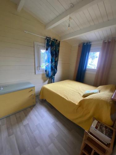 a bedroom with a yellow bed and two windows at Chalet Horizon Mer in Conca