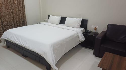 a bedroom with a large bed and a black chair at Hotel Tamilnadu Trichy in Tiruchirappalli
