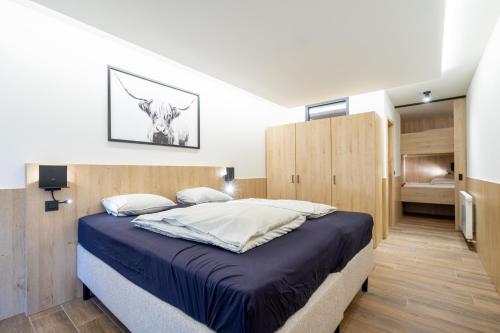 a bedroom with a king sized bed and wooden cabinets at Gîte DDS - Bridge into nature! in Manhay
