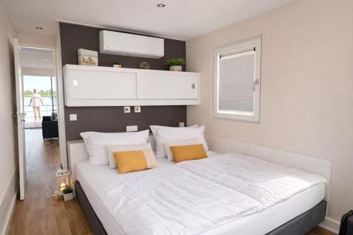 a bedroom with a large white bed with two orange pillows at Floatinghouse Sunday in Ribnitz-Damgarten
