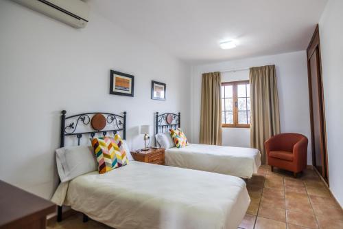 a hotel room with two beds and a chair at Villas & Apartamentos Tao Mazo in Lajares