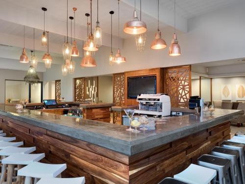 a bar in a restaurant with white chairs and lights at ANEW Resort Hunters Rest Rustenburg in Rustenburg