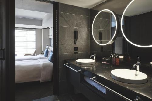 two sinks in a bathroom with a bed and mirrors at Dhawa Yura Kyoto in Kyoto