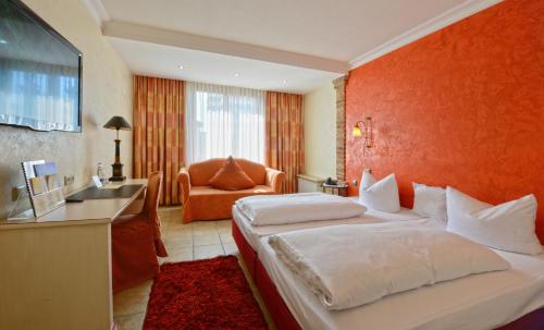 a hotel room with a large bed with an orange wall at Gasthaus Gästekiste in Augsburg
