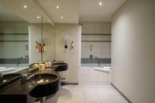 a bathroom with three sinks and a large mirror at Hotel Les Jardins De La Molignée in Dinant