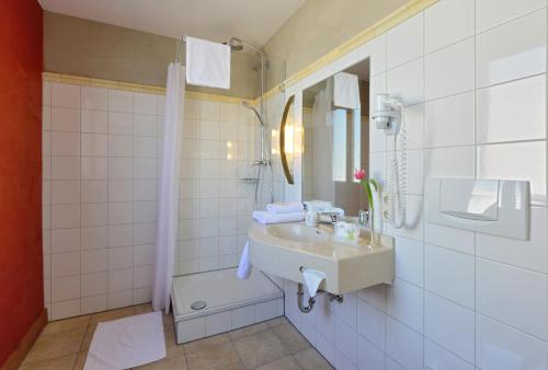 a bathroom with a sink and a mirror and a shower at Gasthaus Gästekiste in Augsburg