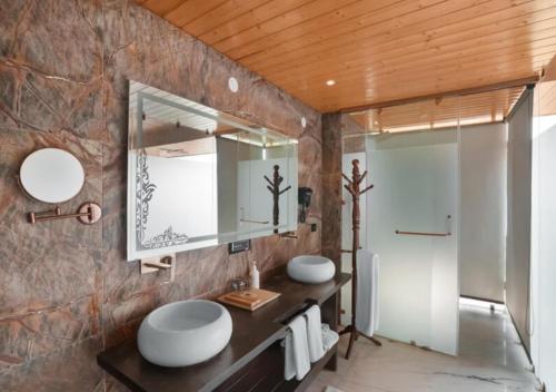 a bathroom with two sinks and a mirror at Aureva Shaantam Resorts & Spa - Rishikesh in Rishīkesh