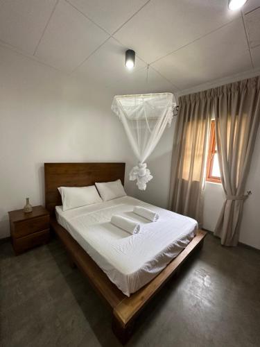 a bedroom with a bed with white sheets and a window at SAHAS Villa - Private Riverfront Garden Retreat in Beruwala in Beruwala