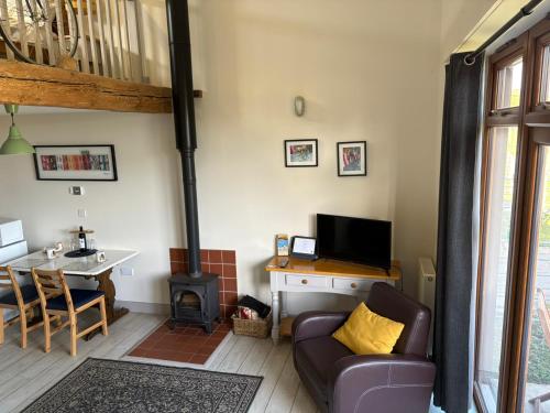 a living room with a couch and a stove at Bike Shed 1-Bed Cottage Sleeps 2 Pet Friendly in Shorwell