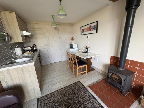 a kitchen with a stove and a table in a room at Bike Shed 1-Bed Cottage Sleeps 2 Pet Friendly in Shorwell