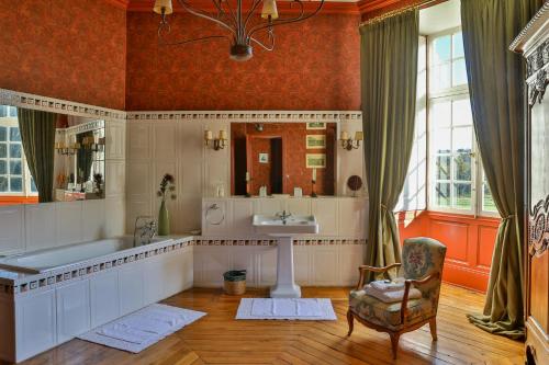 a bathroom with a tub and a sink and a chair at Chateau de Vaux in Yvré-lʼÉvêque