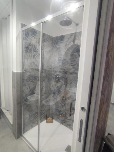 a shower in a room with a stone wall at Le stanze del Corso in Monreale