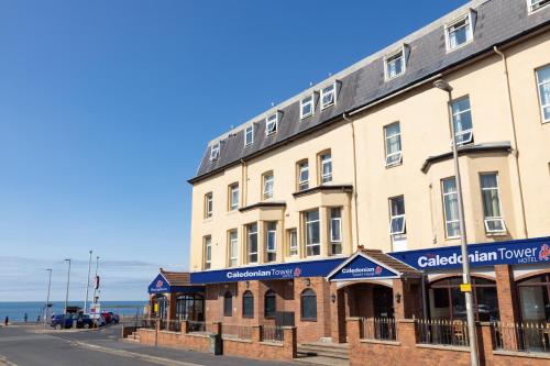 a building on a street with the ocean in the background at The Caledonian Tower Hotel in Blackpool