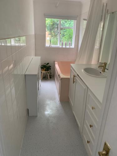 a bathroom with a sink and a pink bath tub at Richmond Escape in Richmond upon Thames
