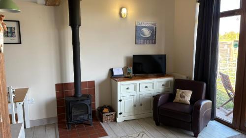 a living room with a stove and a chair at Poachers Hut 1-Bed Cottage Sleeps 2 Pet Friendly in Shorwell