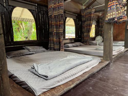 two large beds in a room with windows at Loopmoto Riverside Homestay in Làng Lap