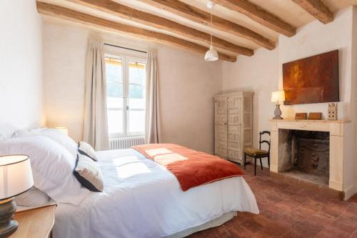 a bedroom with a large white bed and a fireplace at Clos Chartrain in La Chartre-sur-le-Loir