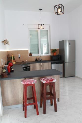 a kitchen with a counter and two red stools at Villa Helia in Kos