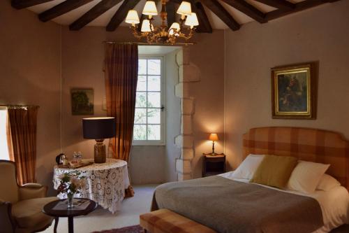 a bedroom with a bed and a table and a window at Chateau de Vaux in Yvré-lʼÉvêque