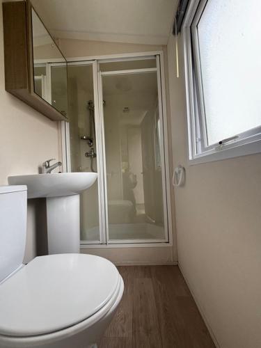 a bathroom with a toilet and a sink and a window at Camping le quinquis in Clohars-Carnoët