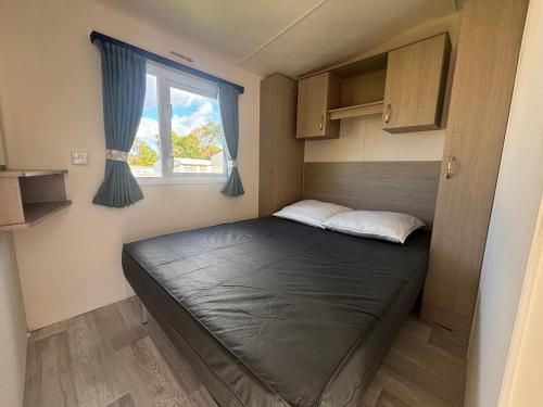 a bed in a small room with a window at Camping le quinquis in Clohars-Carnoët