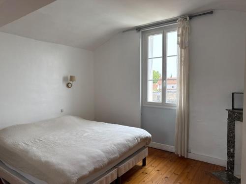 a white bedroom with a bed and a window at Large house - Garden pool in Cognac