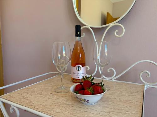 a bottle of wine and two glasses and a bowl of strawberries at Sunlit Village Escape in Kompítsion