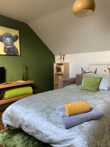 a bedroom with a large bed and a green wall at First floor Pad Carterton near Burford in Shilton