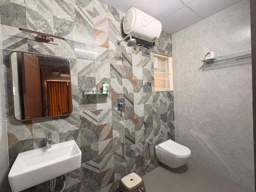 a bathroom with a sink and a toilet and a mirror at Radial Serviced Apartments in Chennai