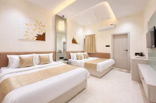 a hotel room with two beds and a television at Sharda Grand in Ujjain
