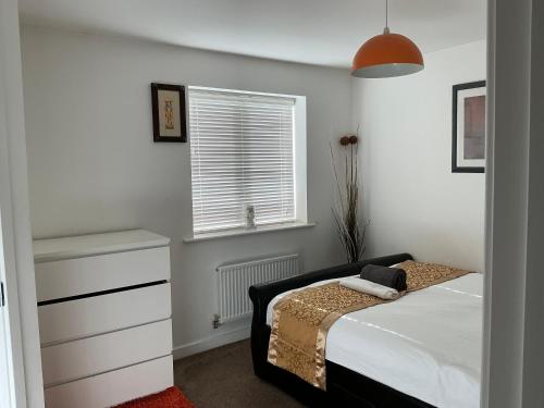 a bedroom with a bed with a dresser and a window at Home away from away in Dartford