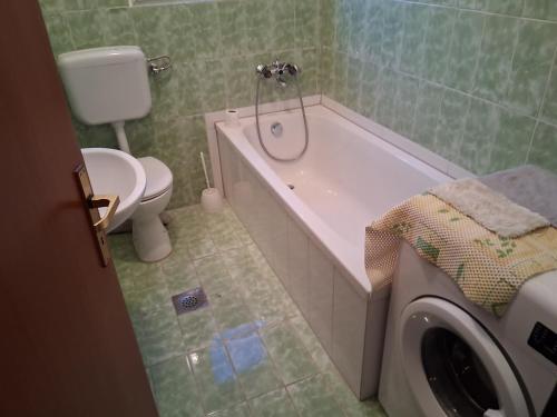 a bathroom with a tub and a toilet and a washing machine at Kampor 211 in Kampor