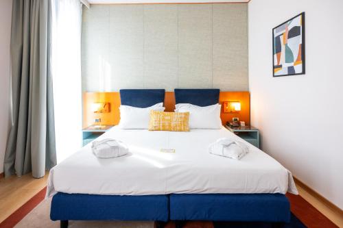 a blue and white bed in a room at voco Parma & Congressi by IHG in Parma
