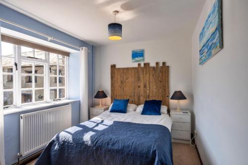 a bedroom with a bed with blue sheets and a window at Finest Retreats - Trimstone Manor, Manor Cottage in Woolacombe