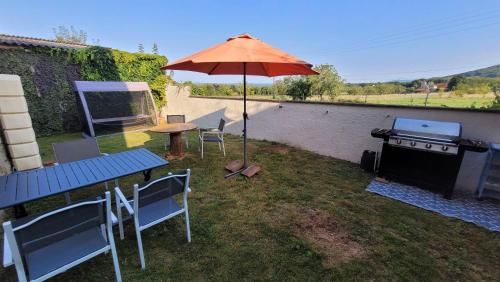 a patio with a table and an umbrella and a grill at Gîte familial avec jardin privatif - près de Rocamadour et Padirac in Saint-Michel-de-Bannières