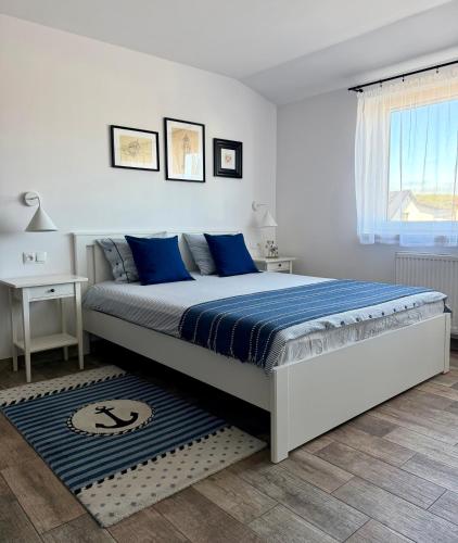 a white bedroom with a large bed with blue pillows at Morza Szum in Dziwnów