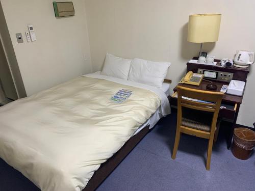 a hotel room with a bed and a desk with a phone at Hotel Sunshine Iwaki in Iwaki