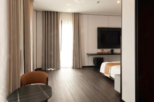 a hotel room with a bed and a table and a television at H- Dragon Hotel in Ðố Sơn